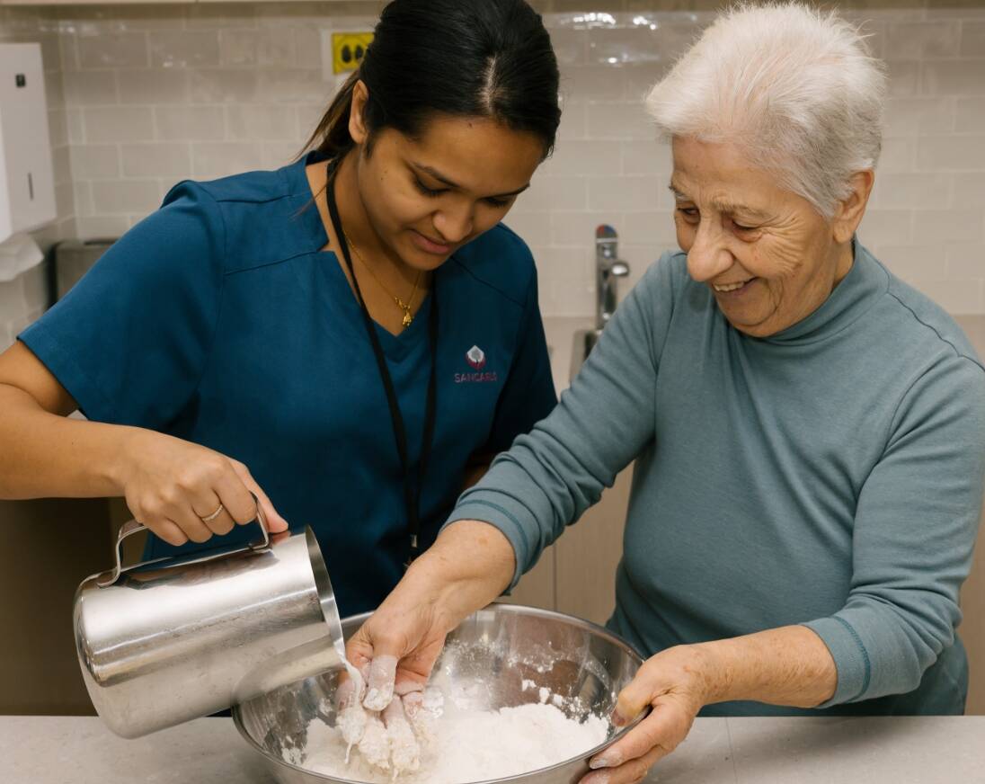 A resident having a great time cooking in a kitchen with a worker.