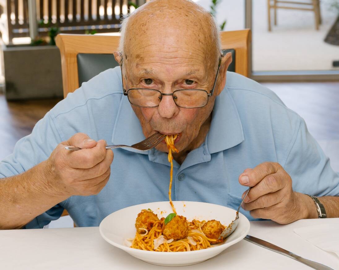 A resident eating a tasty bowl of pasta and meatballs.