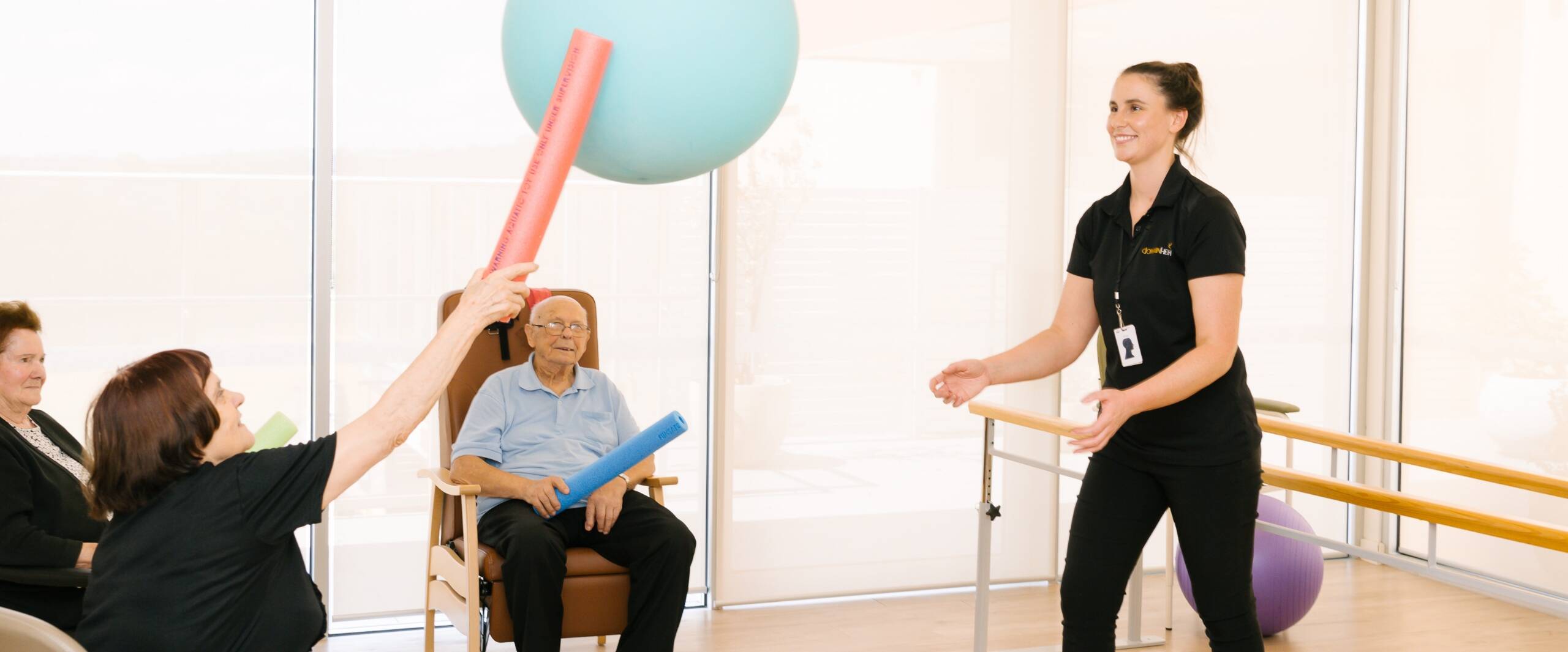 A group of residents playing a game with pool noodles and a ball.