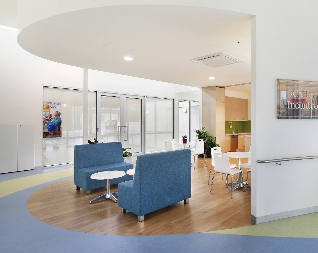 A modern sitting area with comfortable chairs, tables, and a kitchen.